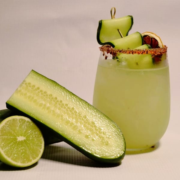 A Mr. Sombrero cucumber margarita with a chili-lime rim, garnished with cucumber slices and a lime.