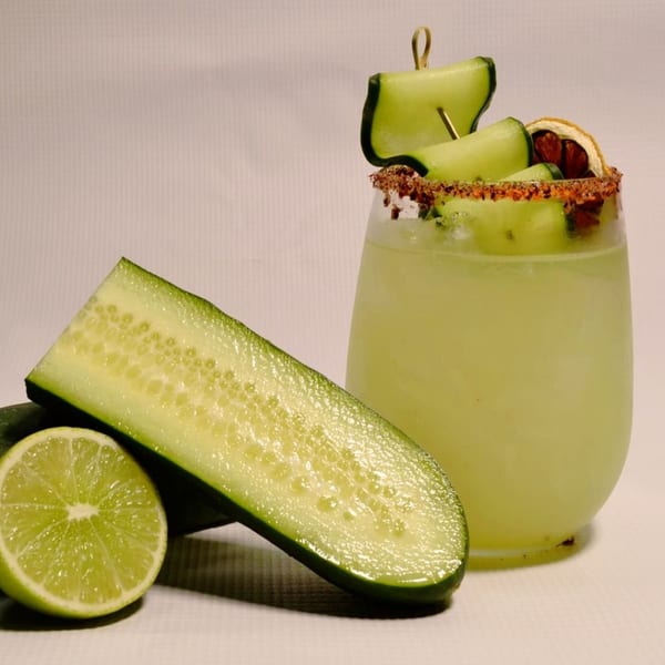 Cucumber margarita with a chili-lime rim, garnished with cucumber slices and a dried orange.