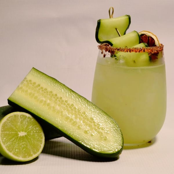 Cucumber margarita with a chili-lime rim, garnished with cucumber slices and a dried orange.