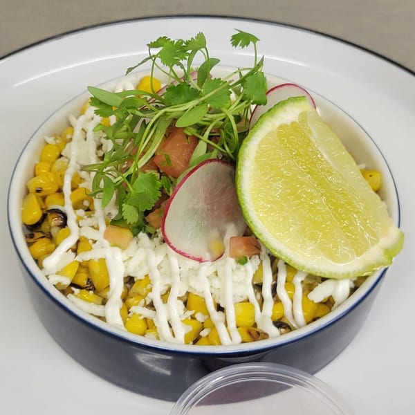 Mr. Sombrero's Mexican street corn with cheese, crema, cilantro, radish, and a lime wedge.