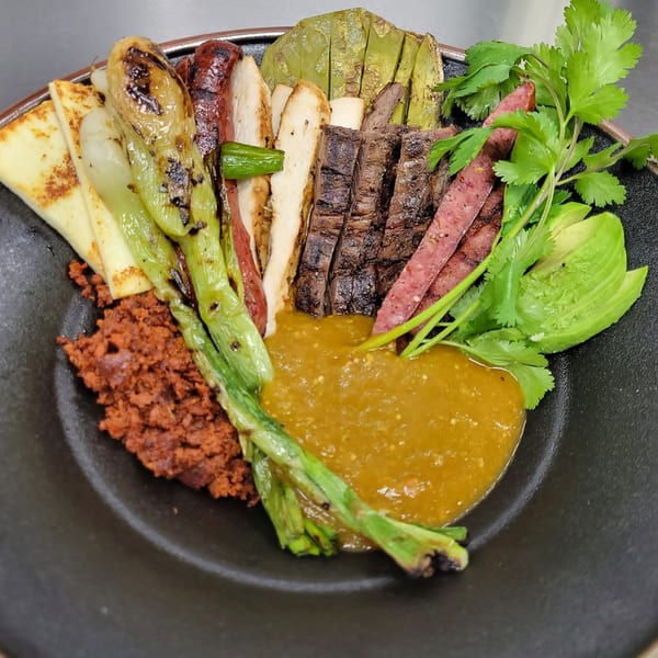 A Mr. Sombrero dish with grilled meats, chorizo, cheese, nopales, avocado, and green salsa.