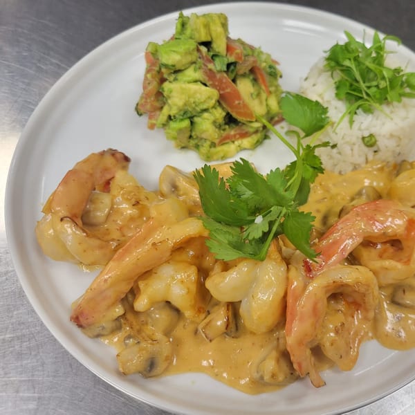 Mr. Sombrero's creamy shrimp dish with rice, avocado salad, and cilantro garnish.