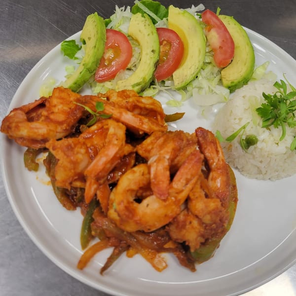 Mr. Sombrero's shrimp dish with rice, avocado, tomatoes, and lettuce on a white plate.