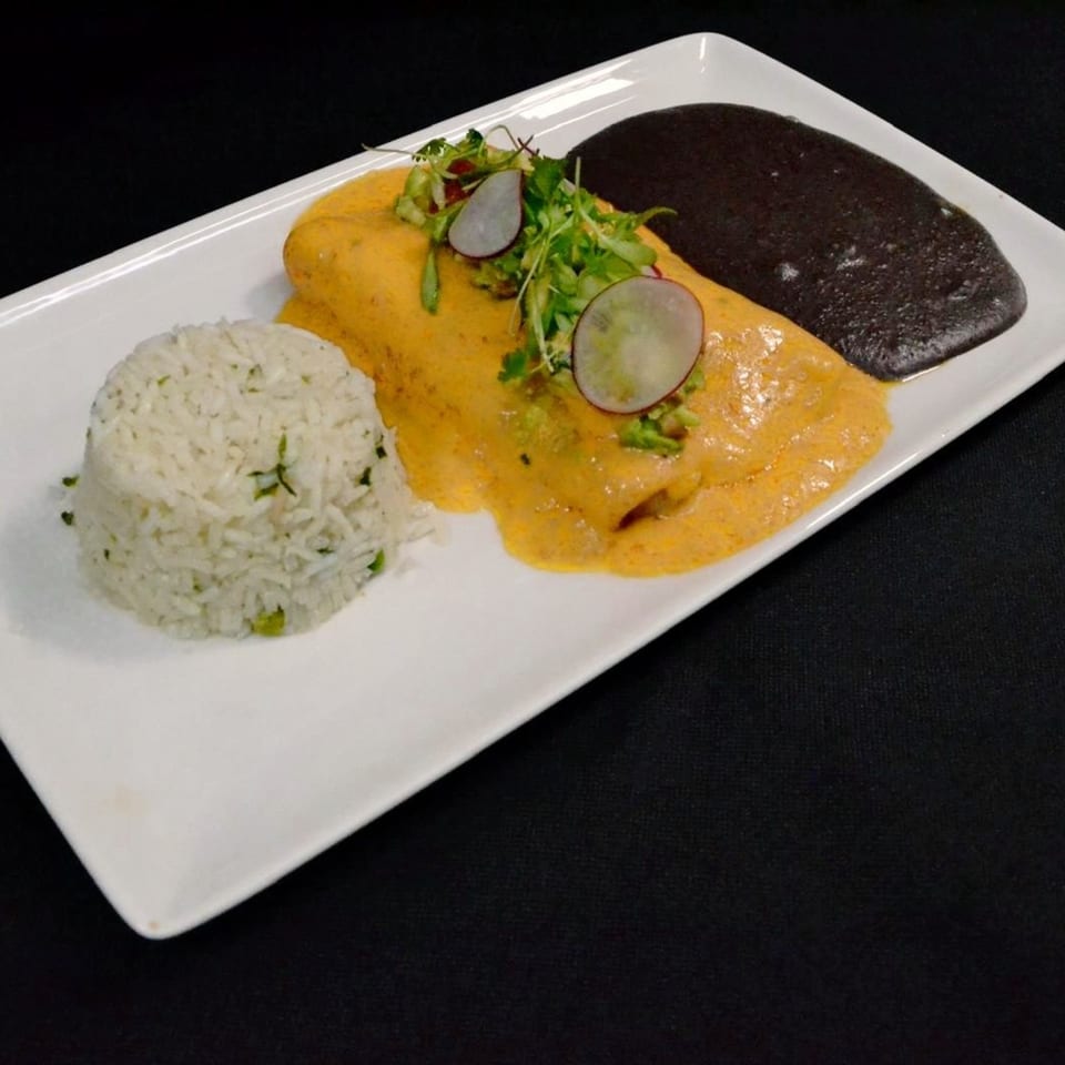 Mr. Sombrero's enchilada with yellow sauce, rice, black beans, and radish garnish on a white plate.