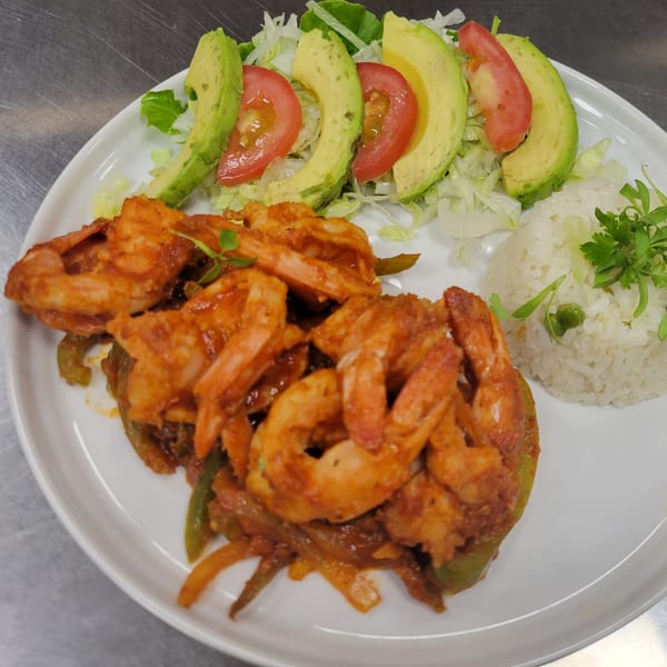 Mr. Sombrero's shrimp fajitas with rice, lettuce, avocado, and tomato on a white plate.