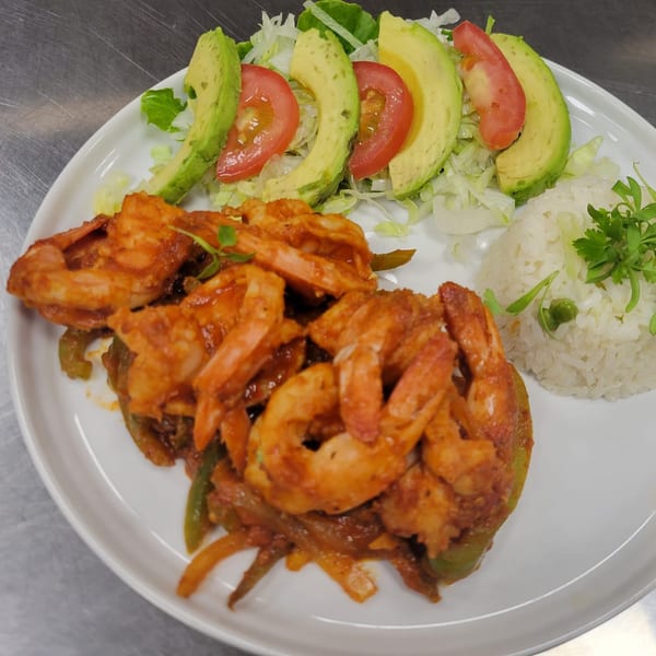 Mr. Sombrero's shrimp fajitas with rice, lettuce, avocado, and tomato on a white plate.